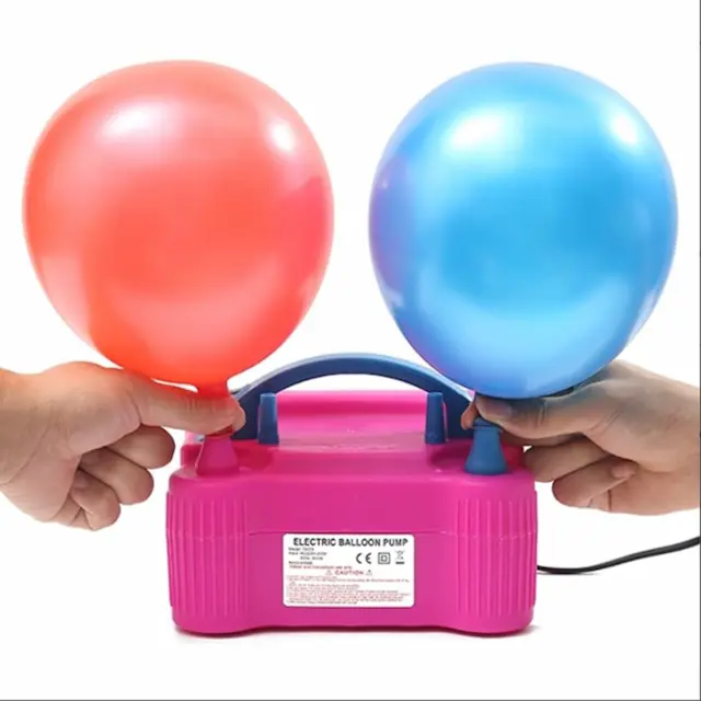 Two hands are pumping a pink electric air pump for inflating balloons. The pump is connected to a power source, and one hand is holding a red balloon, while the other is holding a blue balloon.