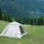 White tent with a screen porch on a grassy field with trees and mountains in the background
